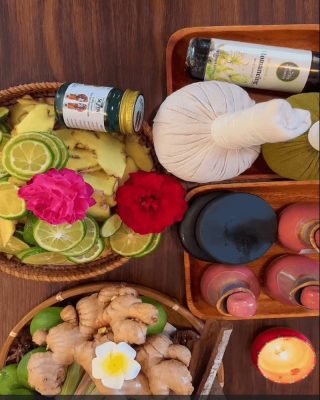 A display of natural spa ingredients including fresh ginger, lime, herbal compresses, and hot stones.
