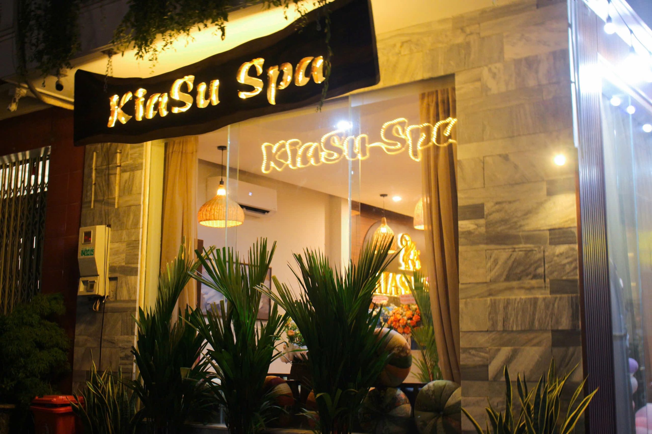 The welcoming entrance of Kiasu Spa in Da Nang at night, with a warm, illuminated sign.