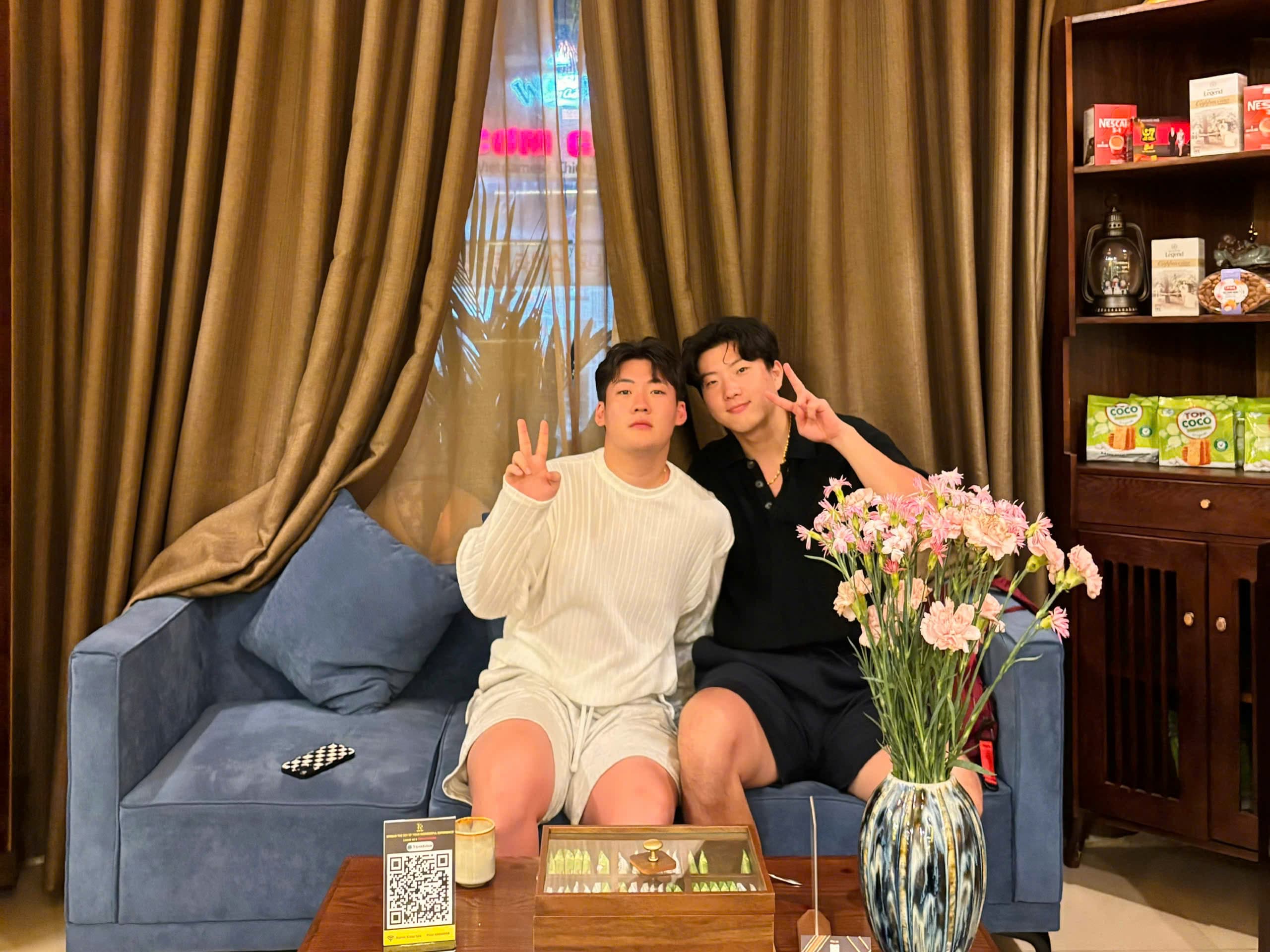 Two happy male Korean guests sitting on a blue sofa at Kiasu Spa's lounge.